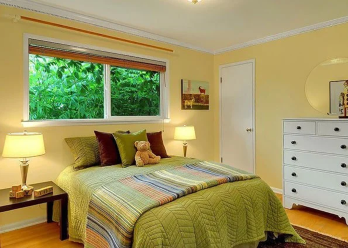 Phòng ngủ màu xanh lá và vàng, kết hợp đèn ngủ, tủ và cửa sổ đơn giản.